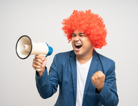 Shout out loud with megaphone. Young Asian man with afro Hairstyle. Funny smiling happiness man with suit jacket announces with a voice about promotions and advertisementsの写真素材
