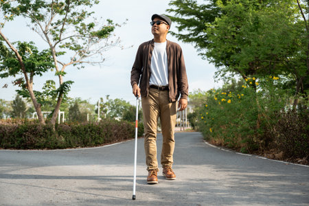 Young blind man walking in city with walking stick. Visually impaired man difficult to traveling on the road wearing sun glasses Cross the road cross the footbridgeの写真素材