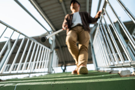 Young blind man walking in city with walking stick. Visually impaired man difficult to traveling on the road wearing sun glasses Cross the road cross the footbridgeの写真素材