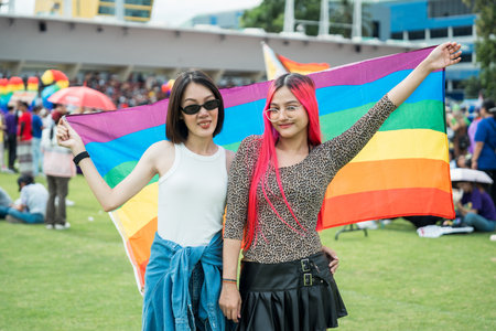 Celebrate in pride month festival. Pride movement transgender asian couple lesbian LGBT holding rainbow flag for freedom. Gatherings of friends in parade communities celebrating LGBTQ+ causes.の写真素材