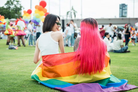 Celebrate in pride month festival. Pride movement transgender asian couple lesbian LGBT holding rainbow flag for freedom. Gatherings of friends in parade communities celebrating LGBTQ+ causes.の写真素材