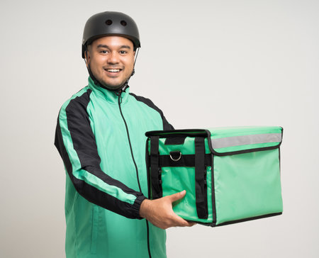 Young asian rider wearing green jacket uniform and bike helmet various action with delivery box. Male delivery service worker. Courier and shipping food service to customer online applicationの写真素材