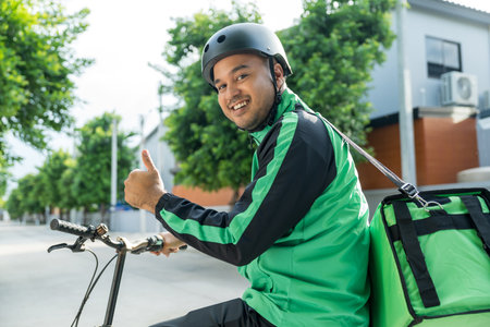 Portrait Rider food delivery man wearing green uniform and helmet cycling a bicycle the food service...