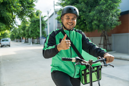 Portrait Rider food delivery man wearing green uniform and helmet cycling a bicycle the food service...