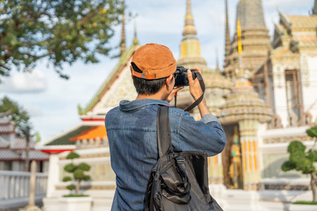 Young Asian traveling backpacker walking in temple at Bangkok Thailand. Happy tourist walking in the downtown street traditional ancient temple. Holiday vacation time touristの写真素材