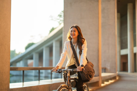 Young Asian business woman riding bicycle in urban city. Sustainable save energy lifestyle. Commute and carbon neutral transportation net zero. Asian woman cycling bike on the street road.の写真素材