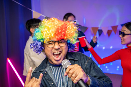 New Year's Party. Group of asian friend party in the house with disco light having fun and dancing together. Enjoy Singing karaoke listening music drinking beer celebration in new year happy hour.の写真素材
