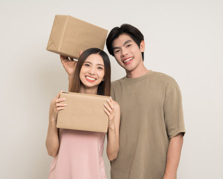 Happy asian couple attractive in various action gesture receive the parcel box cardboard delivery on isolated white background. Cheerful Smiling young man and woman holding box parcel of moving houseの写真素材