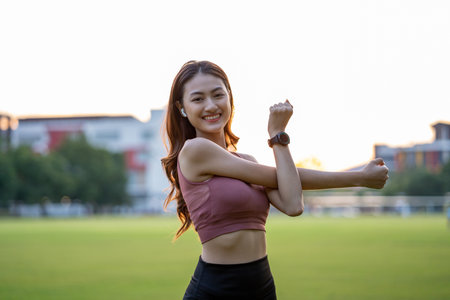 Healthy and fit asian woman wearing sportswear warming up in the park at sunrise. Confident young...