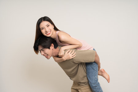 Piggyback ride Happy asian couple attractive in various action gesture standing on isolated white background. Cheerful Smiling young man and woman fun with piggyback rideの写真素材