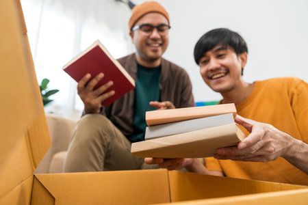 The asian family buying new house. Moving relocation with parcel box cardboard. They relax in living room lifestyle.の写真素材