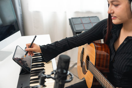 Professional Musician with condenser microphone and tablet for Mixing Mastering music. Music composer woman composing a song with guitar and piano keyboard at digital Recording home studioの写真素材