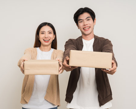 Happy asian couple attractive in various action gesture receive the parcel box cardboard delivery on isolated white background. Cheerful Smiling young man and woman holding box parcel of moving houseの写真素材