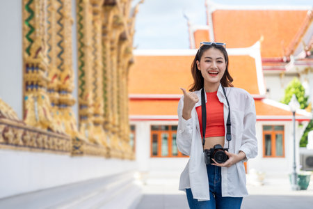 Young Asian woman traveling backpacker walking in temple at Bangkok Thailand. Happy female tourist walking in the downtown street traditional ancient temple. Holiday vacation time touristの写真素材