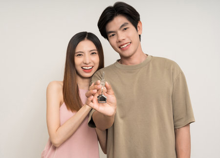 Happy family asian couple in various action gesture holding house key on isolated white background. Cheerful Smiling young man and woman buy new home showing key of the houseの写真素材