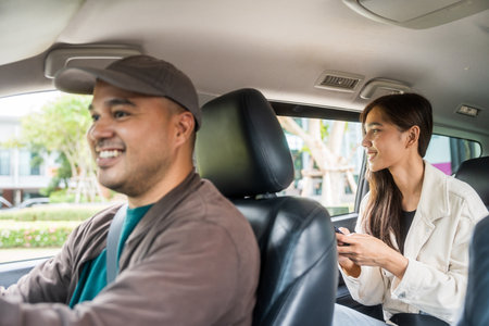 Young asian woman traveling in the downtown city with taxi driver service. Female passenger sitting in backseat calling taxi driver by application.の写真素材