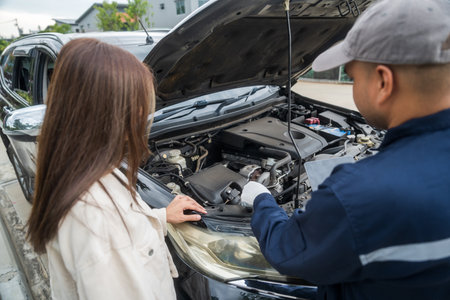 Young female driver call Auto mechanic car service. Broken Down car outside the road help and support customer. Discussing repairs problems to vehicle.の写真素材