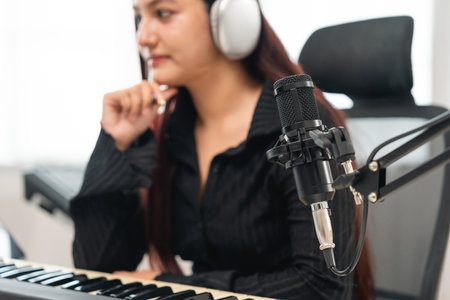 Professional Musician with condenser microphone and tablet for Mixing Mastering music. Music composer woman composing a song with guitar and piano keyboard at digital Recording home studioの写真素材