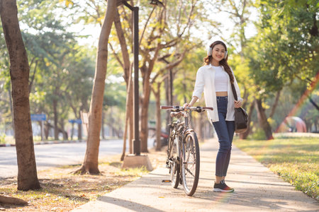 Young Asian woman riding bike in nature public park. Sustainable save energy lifestyle. Commute and carbon neutral transportation. Asian woman cycling bike on the nature road.の写真素材
