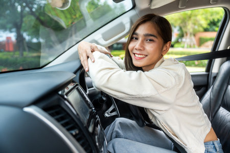 Young beautiful asian business women getting new car. Happy smiling female driving vehicle on the road hugging steering wheel touching detail car interior. Business woman buying driving new carの写真素材