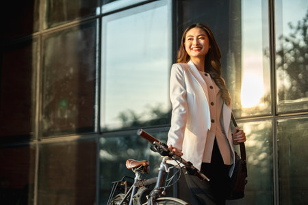 Young Asian business woman riding bicycle in urban city. Sustainable save energy lifestyle. Commute and carbon neutral transportation net zero. Asian woman cycling bike on the street road.の写真素材