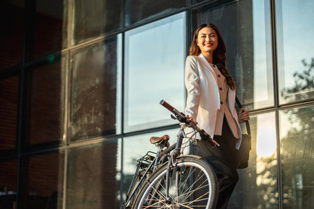 Young Asian business woman riding bicycle in urban city. Sustainable save energy lifestyle. Commute and carbon neutral transportation net zero. Asian woman cycling bike on the street road.の写真素材