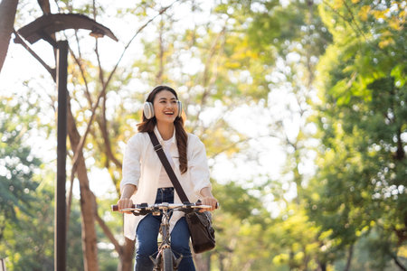 Young Asian woman riding bike in nature public park. Sustainable save energy lifestyle. Commute and carbon neutral transportation. Asian woman cycling bike on the nature road.の写真素材