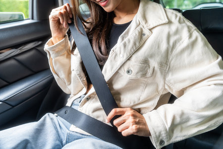 Relaxing moment of beautiful woman sitting in car back seats with safety belt and look out in the window. Female happy in car while traveling on the road to your destination.の写真素材