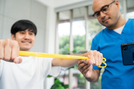 Physical therapy. Male Nurse aids young man in recovering from spine injury and providing orthopedic...