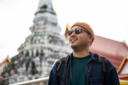 Young Asian traveling backpacker walking in temple at Bangkok Thailand. Happy tourist walking in the downtown street traditional ancient temple. Holiday vacation time touristの写真素材