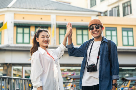 Young Asian couple man and woman traveling backpacker in Khaosan Road outdoor market in Bangkok Thailand. Happy couple tourist walking in the downtown street traditional marketの写真素材