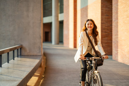 Young Asian business woman riding bicycle in urban city. Sustainable save energy lifestyle. Commute and carbon neutral transportation net zero. Asian woman cycling bike on the street road.の写真素材