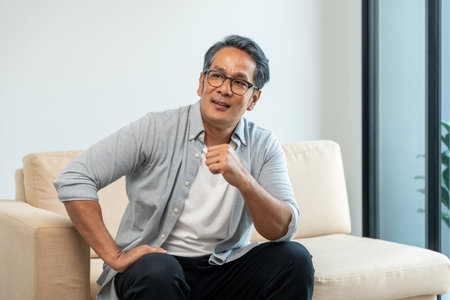 Handsome asian mature old man sitting on sofa couch in living room at home. Happy Portrait of...