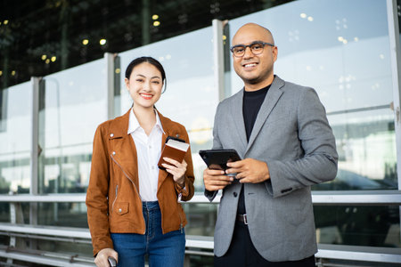 Portrait of confident young business people smiling at camera and traveling with luggage and...