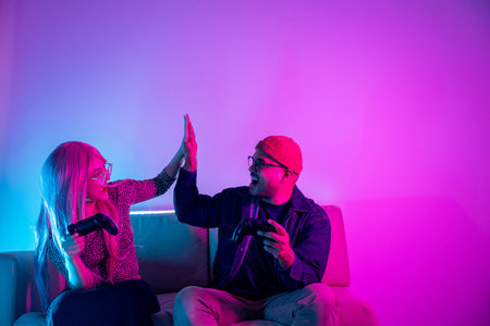 Professional gamer. Young asian man and woman sitting on sofa with joy stick. Happy couple asian...