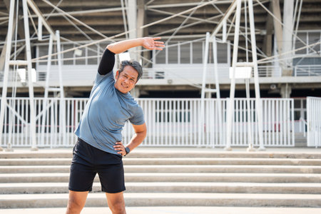 Senior old asian man wearing sportswear warming up before running outdoor. Portraits of Mature man stretching body before running at sport stadium. Training athlete work out at outdoorの写真素材