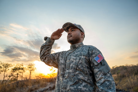 Us Army veteran honors Veterans Day. Man soldier adjusts the US military patch before duty. A US soldier with an American flag patch on his uniform prayers for Memorial Day. Independence Dayの写真素材