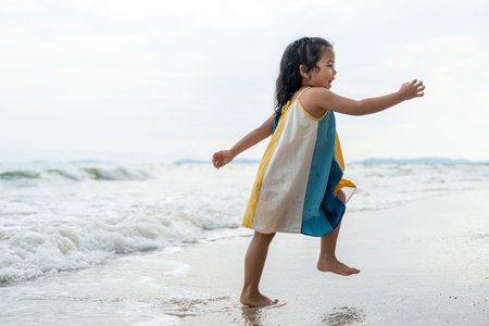 Cheerful adorable little girl having fun outdoor and playing with sand with beach kid toys on the beach in the summer vacation at sunset, happy healthy toddler playful on the tropical seaside.の写真素材