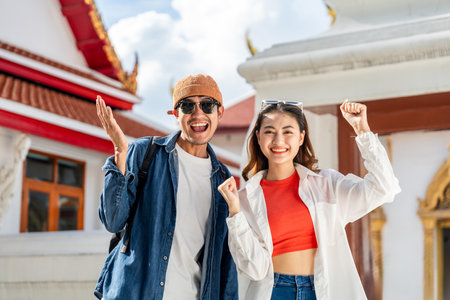 Young Asian couple man and woman traveling backpacker walking in temple at Bangkok Thailand. Happy couple tourist walking in the downtown street. Holiday vacation time touristの写真素材