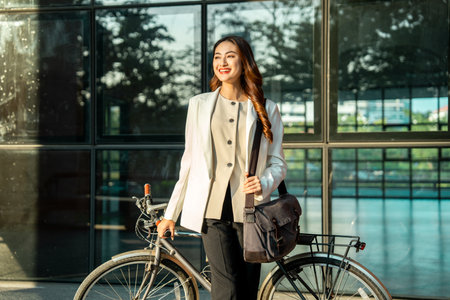 Young Asian business woman riding bicycle in urban city. Sustainable save energy lifestyle. Commute and carbon neutral transportation net zero. Asian woman cycling bike on the street road.の写真素材