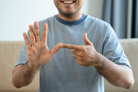 Portrait view of happy young deaf asian man showing sign language and looking at camera at home, a man with hearing disability having communication with hands gestures concept.の写真素材