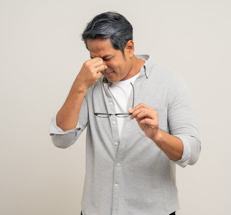 Handsome asian mature old man standing with a headache on an isolated white background. Portrait of...