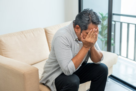 Asian mature old man sitting headache tired on sofa at home. Portrait of serious depression sadness senior asian man. Mature People Depressed problem in lifeの写真素材