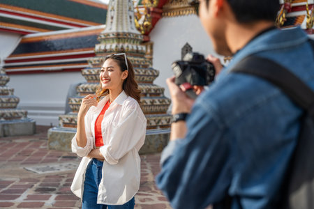 Young Asian couple man and woman traveling backpacker walking in temple at Bangkok Thailand. Happy couple tourist walking in the downtown street. Holiday vacation time touristの写真素材