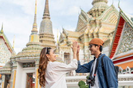 Young Asian couple man and woman traveling backpacker walking in temple at Bangkok Thailand. Happy couple tourist walking in the downtown street. Holiday vacation time tourist