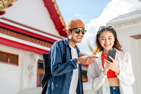 Young Asian couple man and woman traveling backpacker walking in temple at Bangkok Thailand. Happy couple tourist walking in the downtown street. Holiday vacation time touristの写真素材