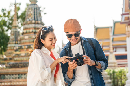 Young Asian couple man and woman traveling backpacker walking in temple at Bangkok Thailand. Happy couple tourist walking in the downtown street. Holiday vacation time touristの写真素材