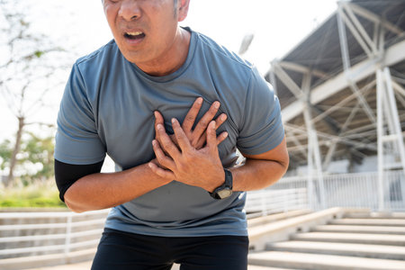 Senior asian man tired during jogging at outdoor sport stadium. Mature asian male intense training workout challenge breathing exhausted. Healthy and activity lifestyle concept.の写真素材