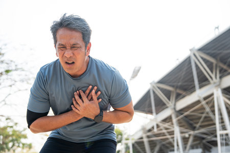 Senior asian man tired during jogging at outdoor sport stadium. Mature asian male intense training workout challenge breathing exhausted. Healthy and activity lifestyle concept.の写真素材