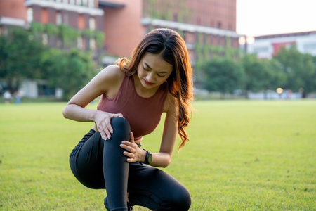 A runner has sore knees because she has been running for too long. Exercising until the injury. Training athlete work out at outdoor concept.の写真素材